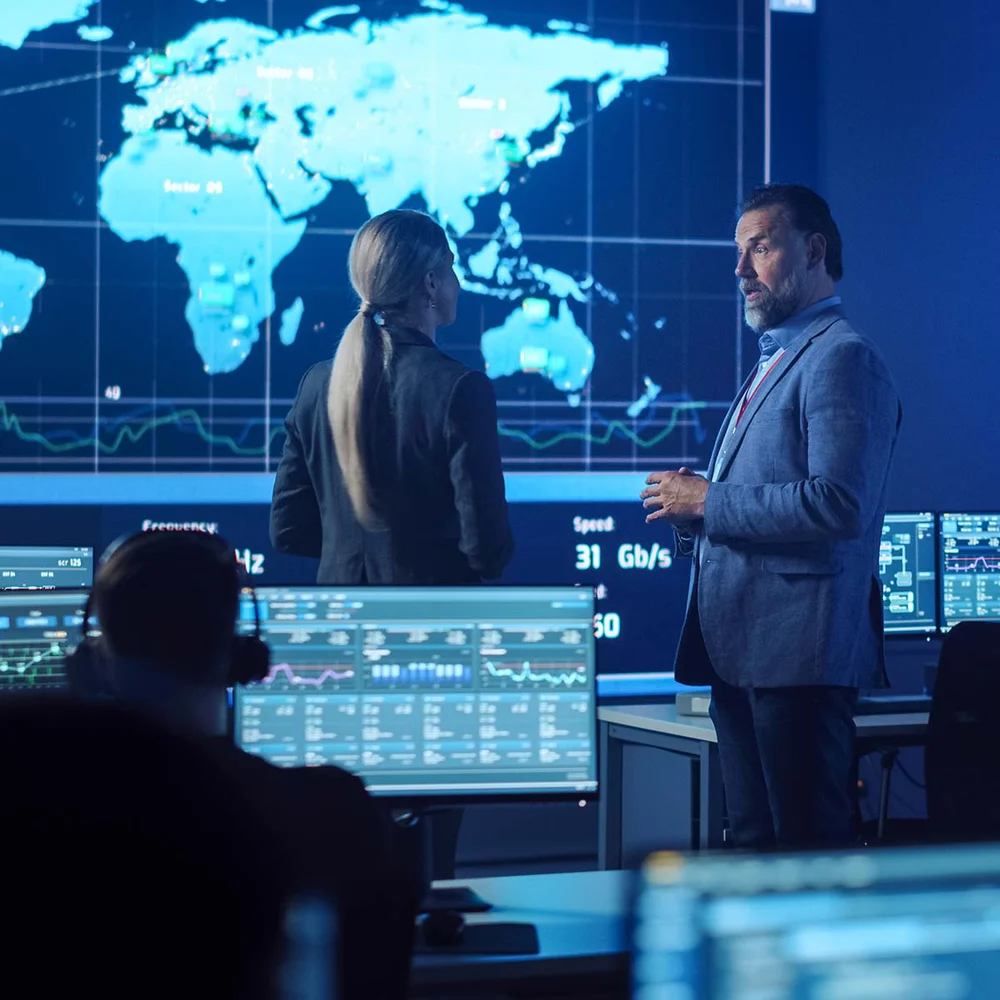 A GIS specialist onboarding a new hire in a control room